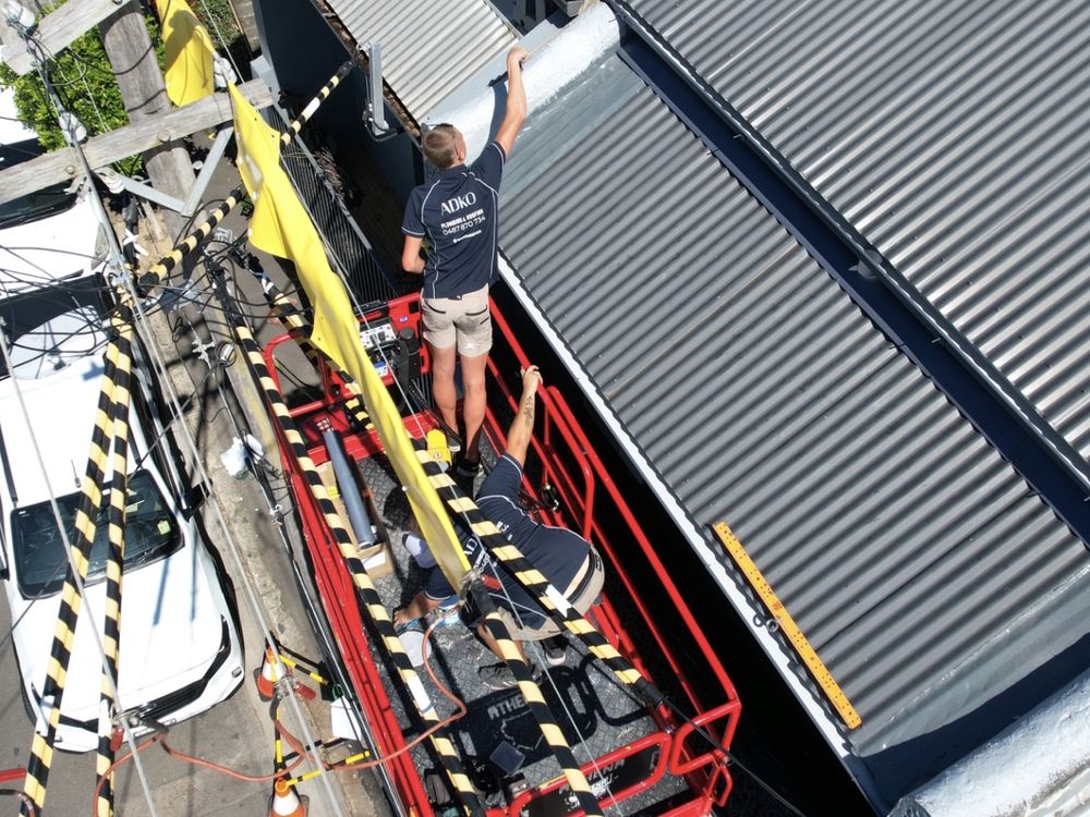 ADKO roofer on an elevated platform beside a metal roof