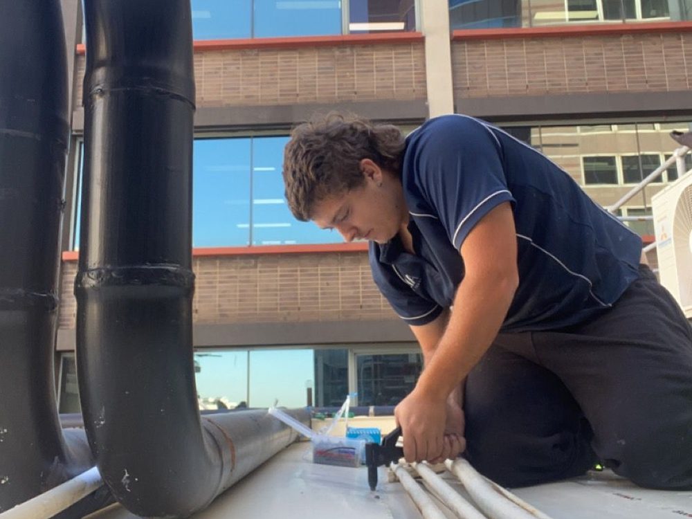 ADKO roofer sealing a metal box gutter on a commercial building
