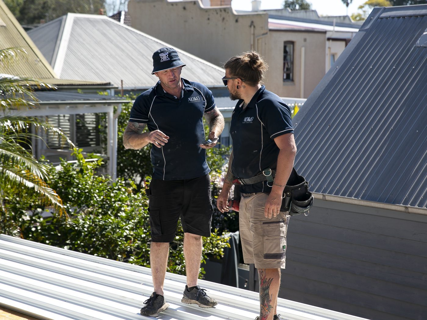 Two ADKO roofers talking through the job on a new metal roof