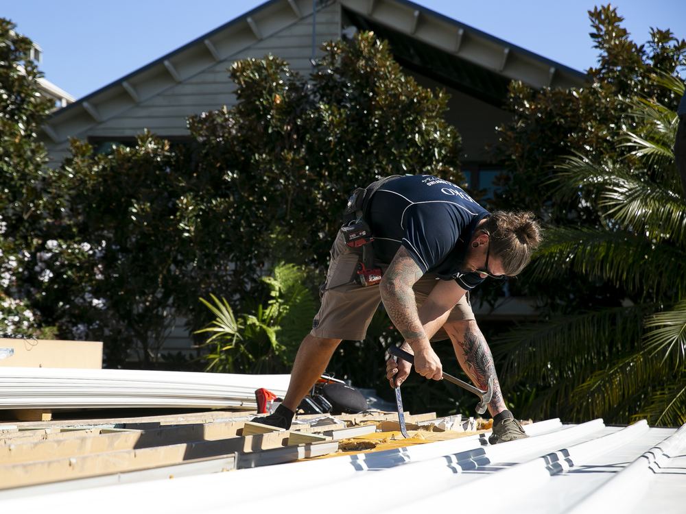 ADKO roofer fixing new metal roofing sheets